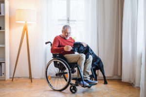 Elderly man in wheelchair smiling with his dog.