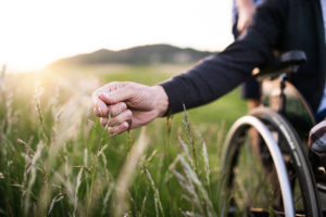 Closeup of person in wheelchair touching grass in field