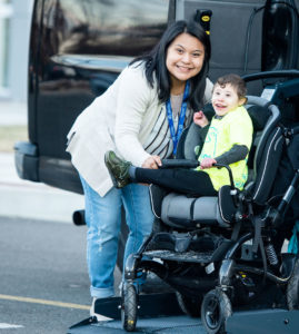 Special child in wheelchair posing for camera outside his wheelchair van