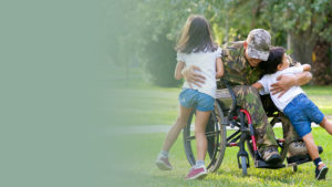 Veteran in wheelchair outside hugging children