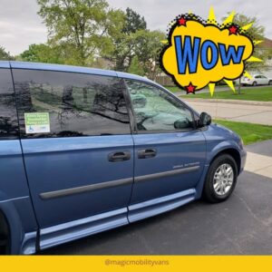 Blue MagicMobility wheelchair minivan with a "Wow" graphic and sign for extra space for ramp or lift. Parked in a suburban neighborhood. Grass and trees in view.